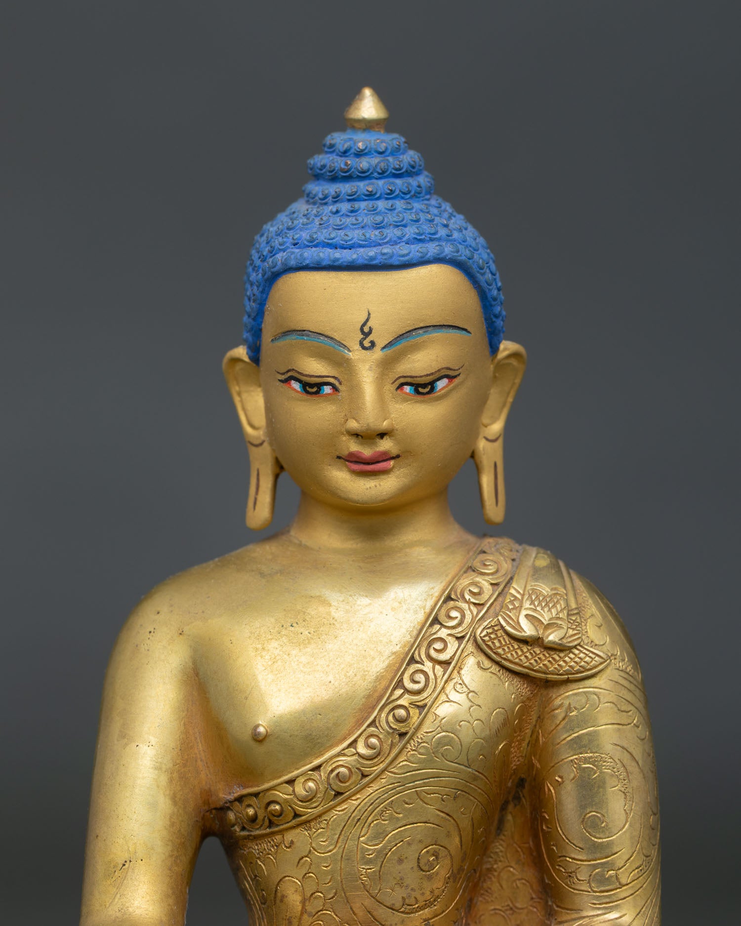 Close up face of Shakyamuni Buddha featuring a gold painted face and peaceful enlightened presence