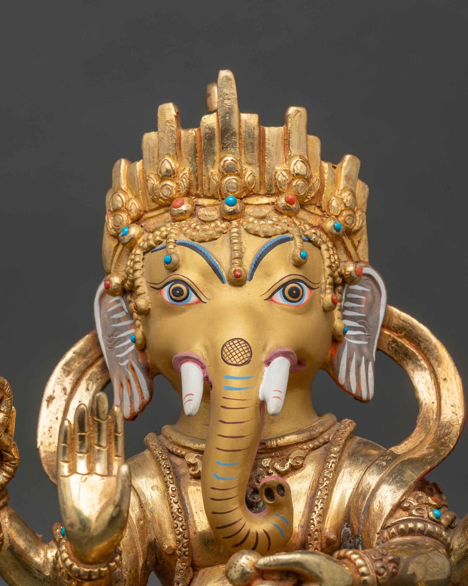 Close up Ganesh face serene expression lotus throne turquoise coral Himalayan sculpture
