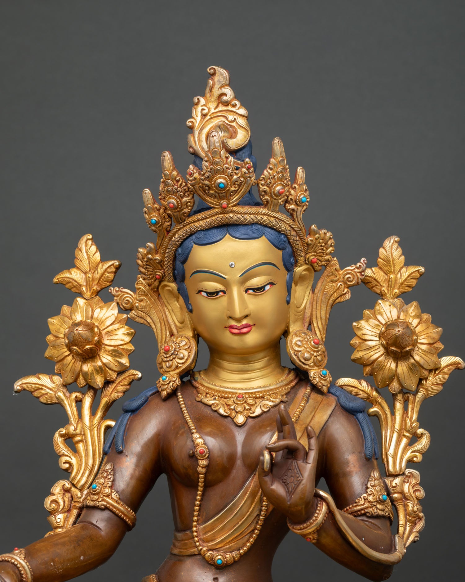 Close-up green tara bodhisattva face with 24k gold painted details and serene expression