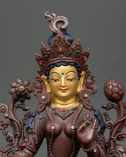 Close up Green Tara Buddhist statue with gold painted face and gemstones.