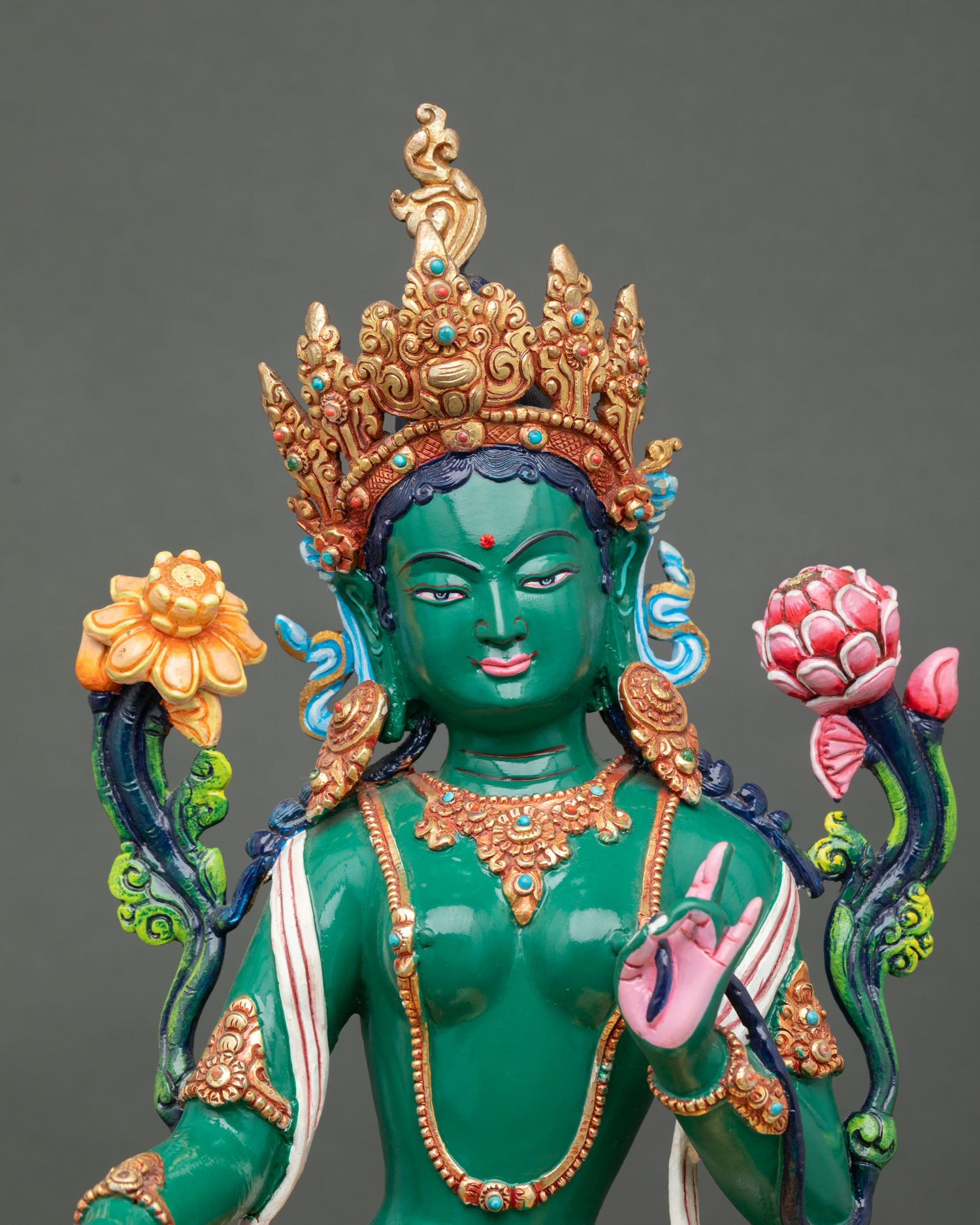 Close up Green Tara face detail serene expression hand painted acrylic colors utpala flower Tibetan goddess compassion statue