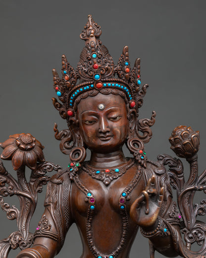 Close up green tara face serene expression gold gilded details Himalayan Buddhist sculpture with intricate carving