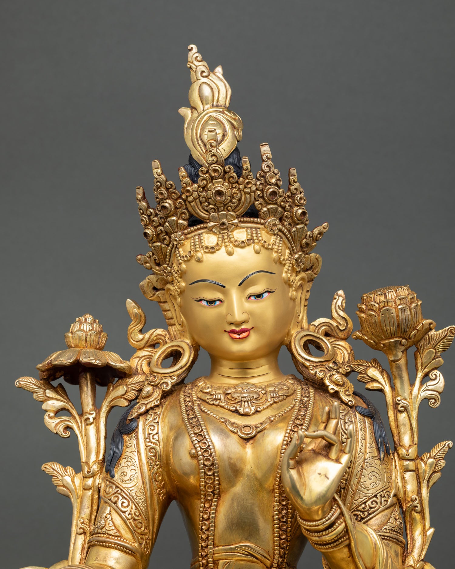 Close up Green Tara, serene expression with crown jewelry, varada mudra and lotus stem detail