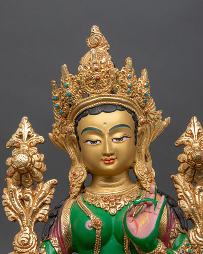 Close-up of Green Tara statue showing gold-painted face and sacred ornaments.