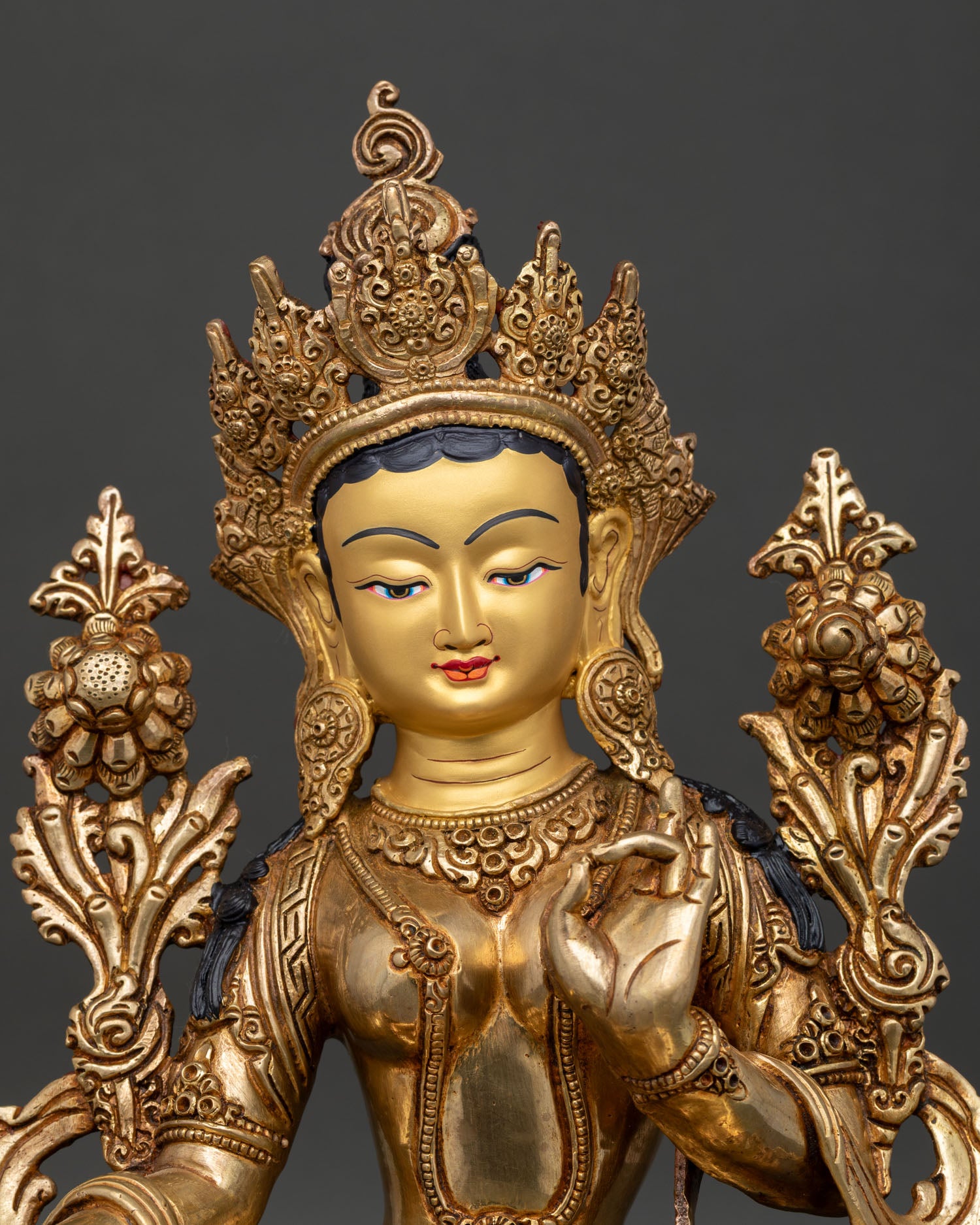 Close up Green Tara statue serene face gold gilded crown intricate jewelry Nepalese Buddhist art