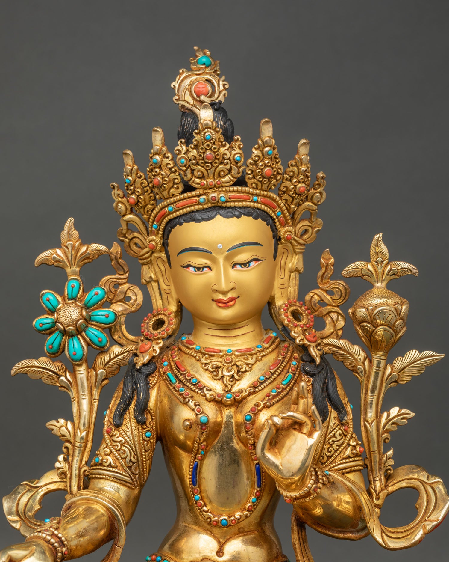 Close up Green Tara statue showing serene gold-painted face and intricately hand-carved designs