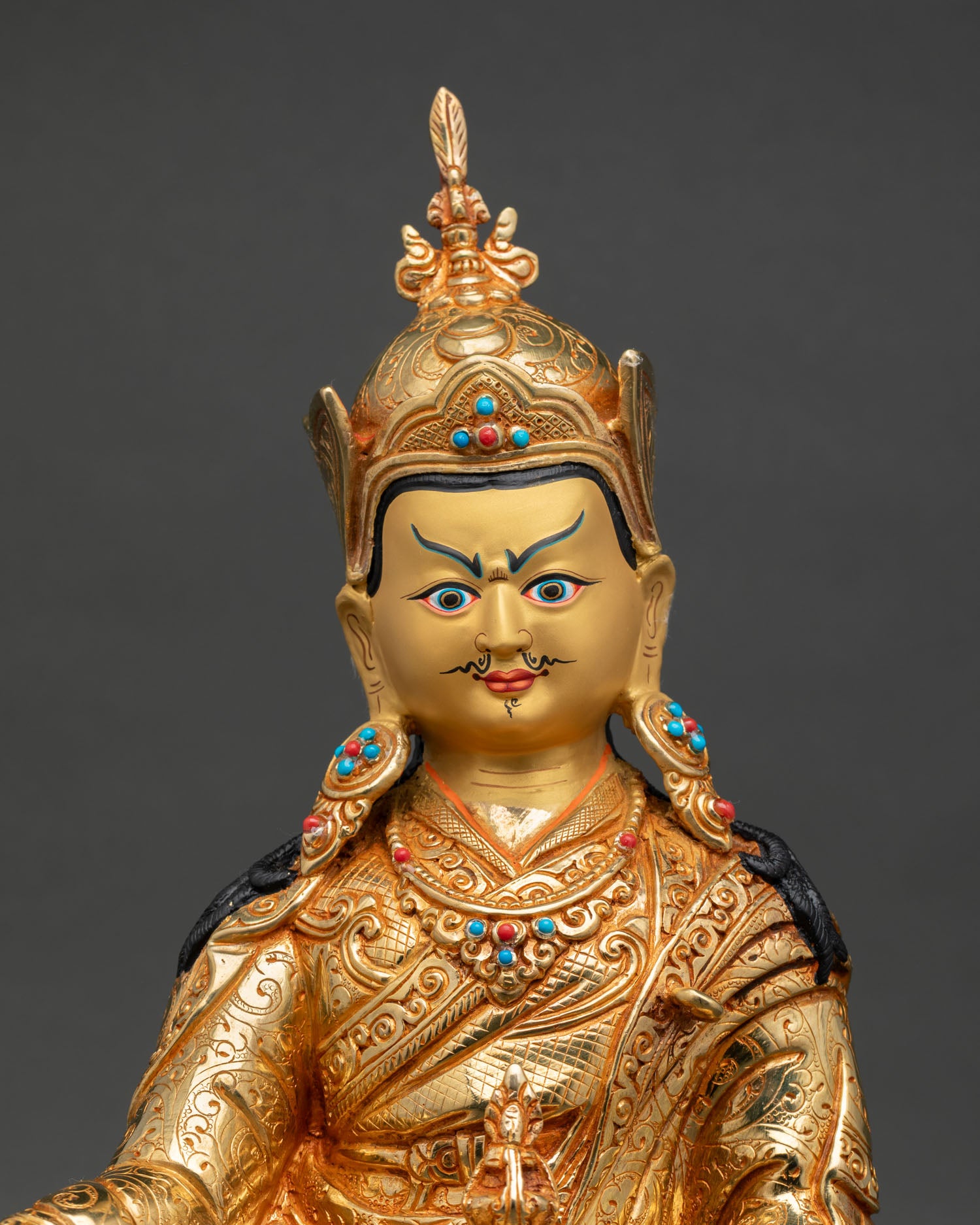 Close up Guru Padmasambhava gold painted face detail Himalayan Buddhist sculpture with ornate crown, sacred Newari craftsmanship