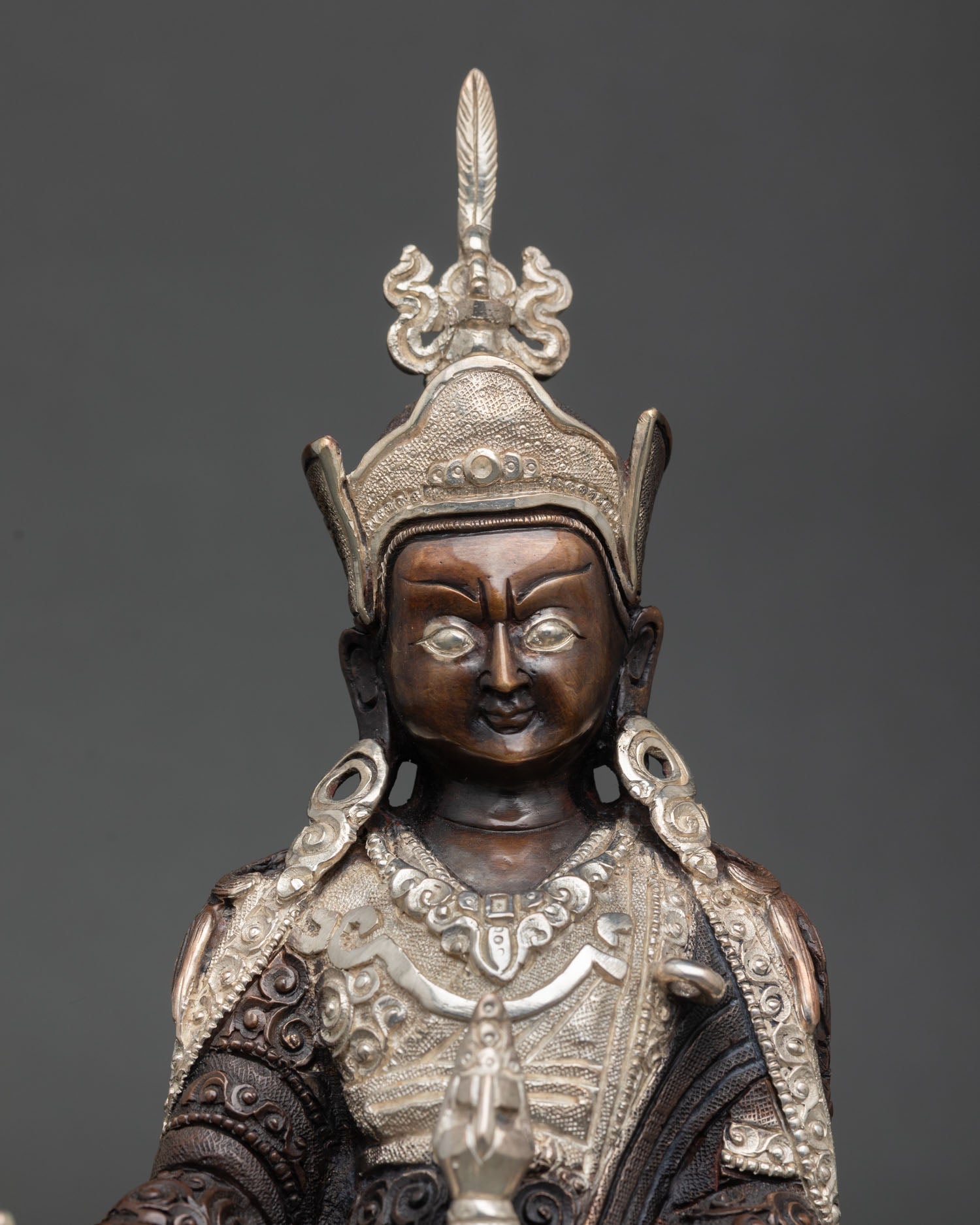 Close up Guru Rinpoche face detailed carving Newari artisan craftsmanship, Buddhist deity 
sacred expression silver plated ornaments