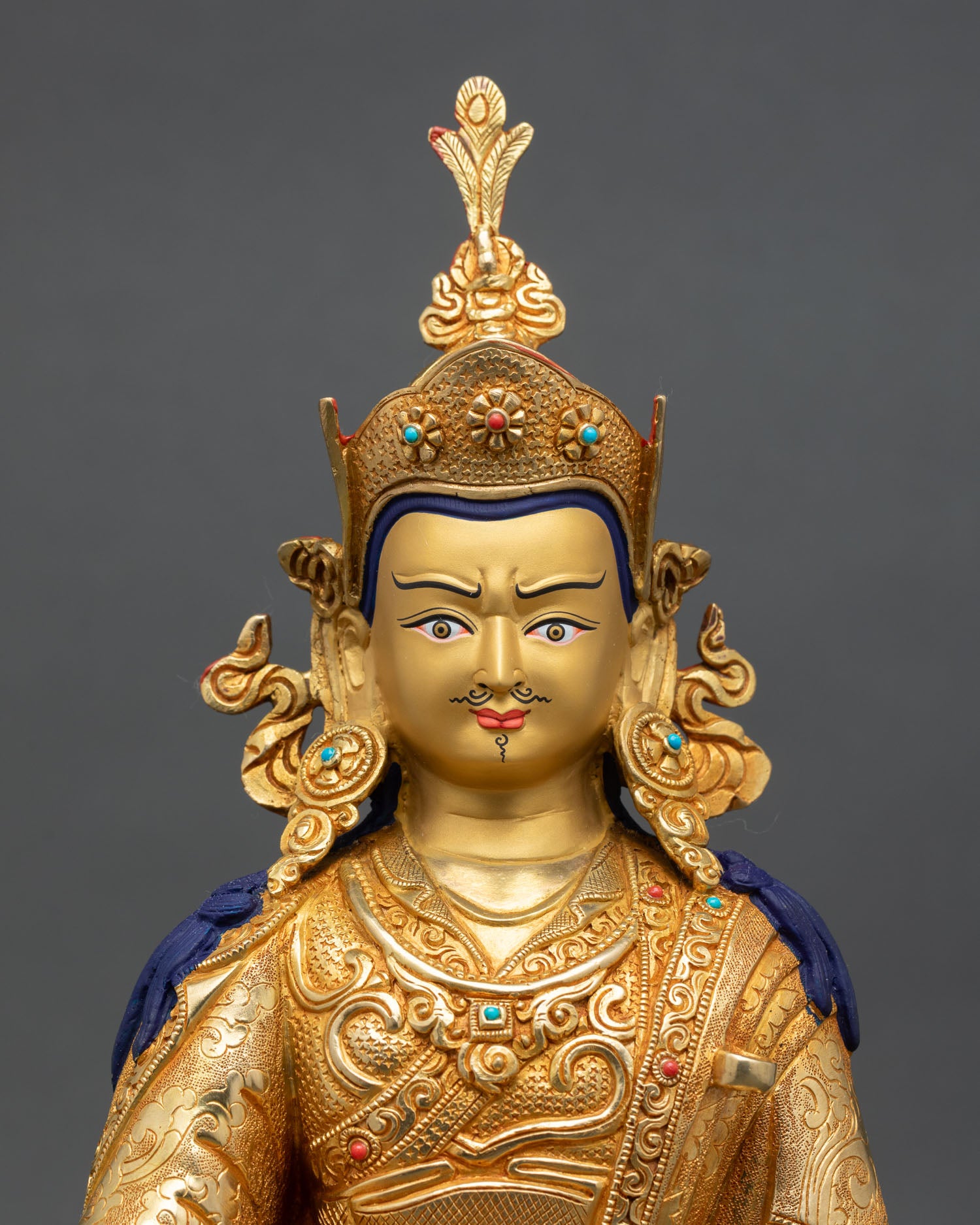 Close up Guru Rinpoche face with gold painted expression serene wisdom and Himalayan Newari artistry detail