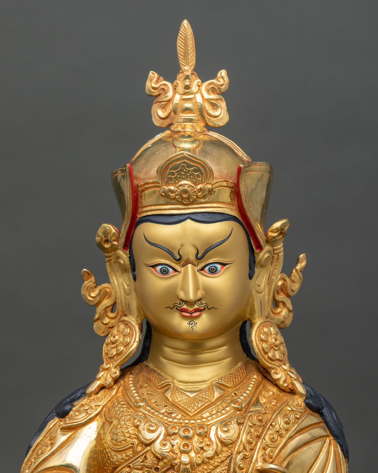 Close up Guru Rinpoche statue face copper gold painted sacred art