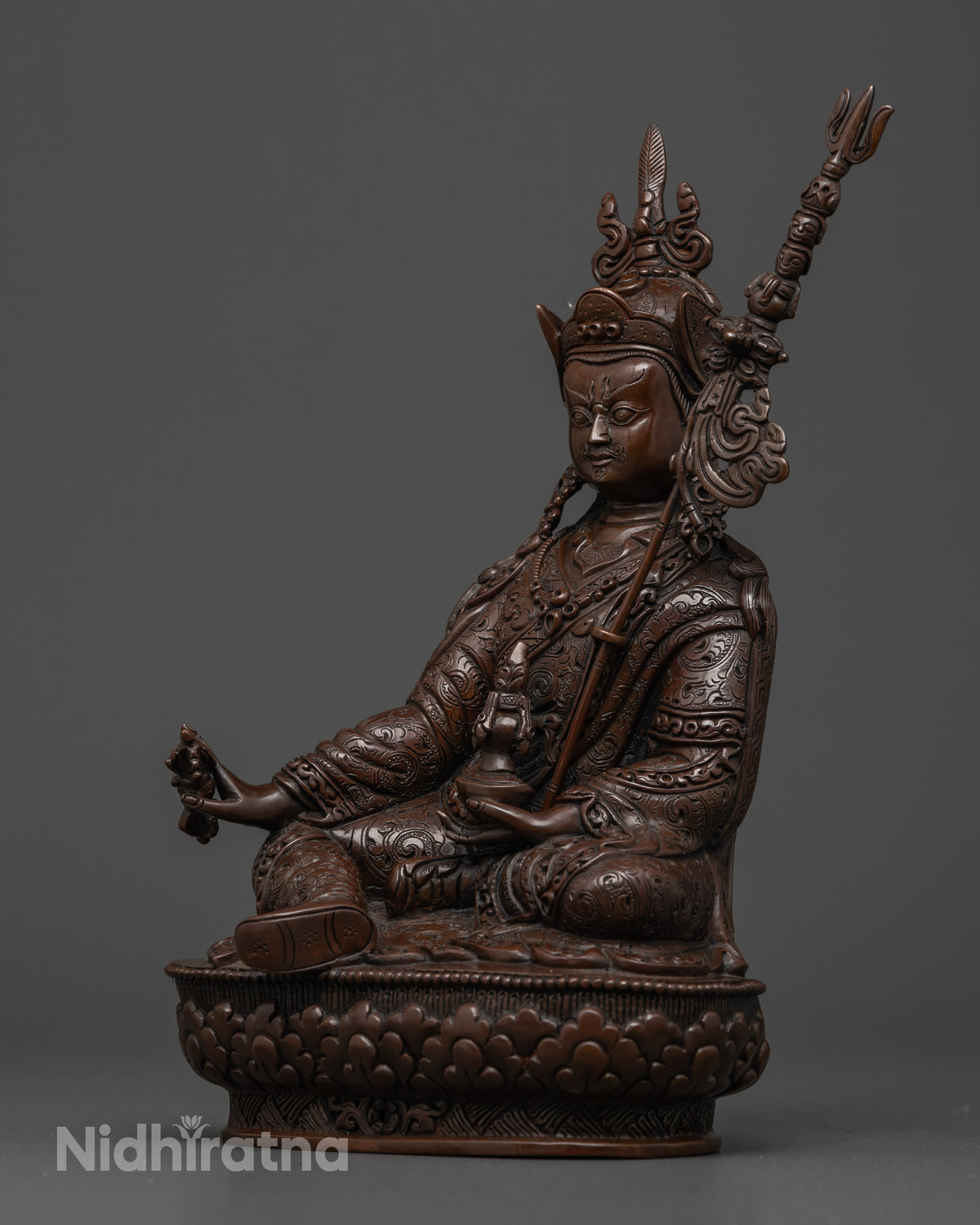 Close-up of Guru Rinpoche holding a vajra and skull cup with a sacred trident