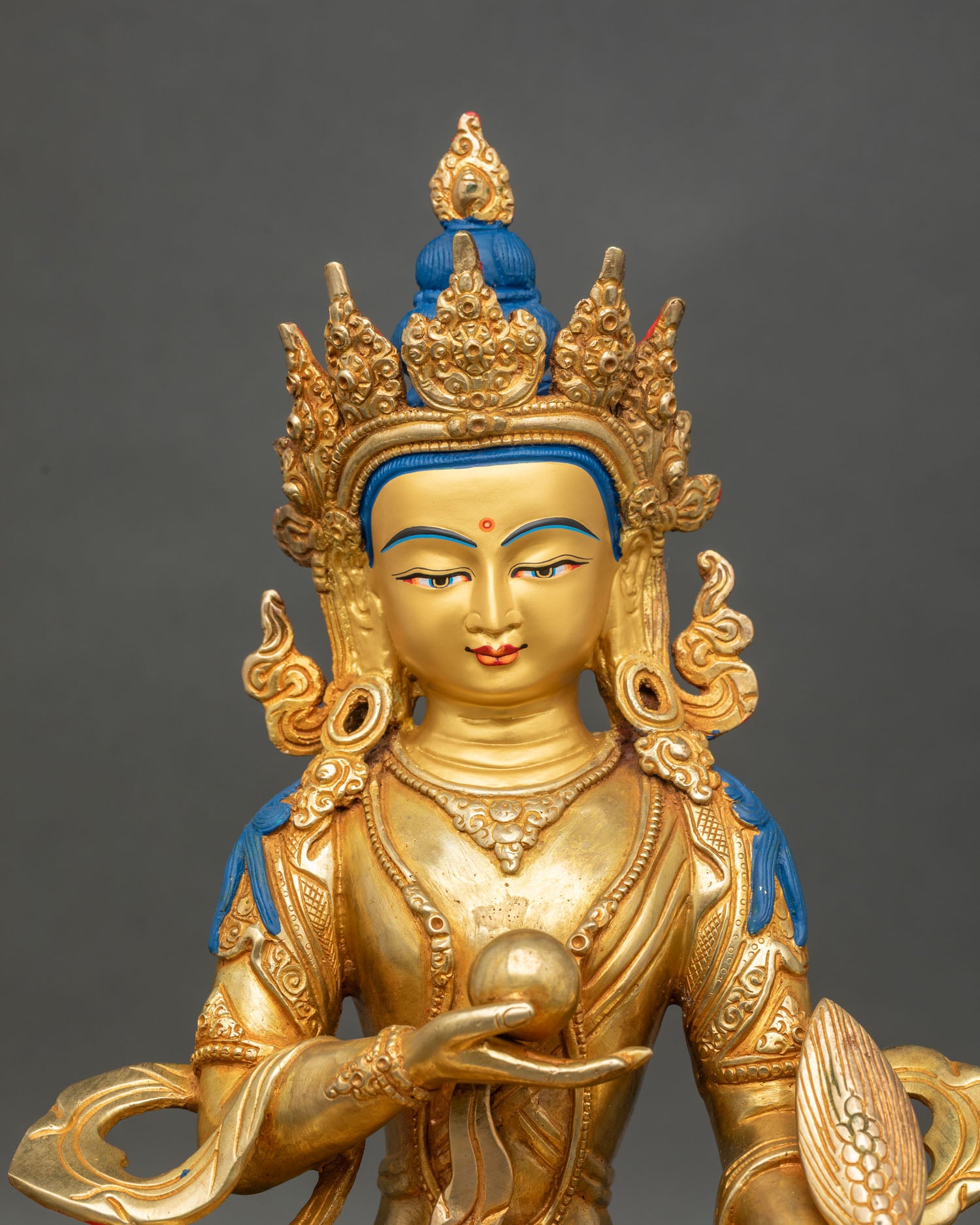 Close up Kshitigarbha face, gold-painted serene expression with intricate details.