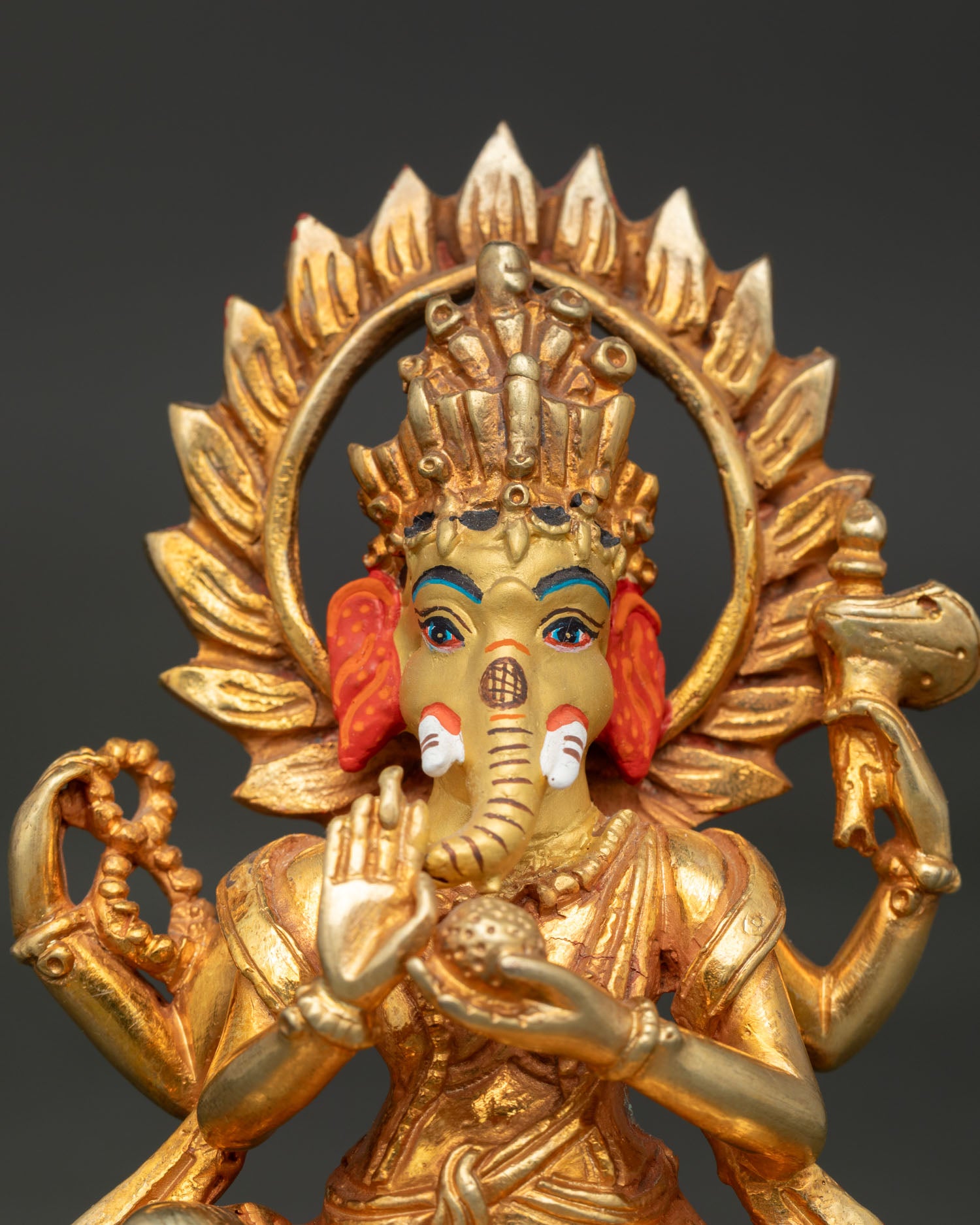 Close-up Lord Ganesha statue with gold-painted face and ornate crown details