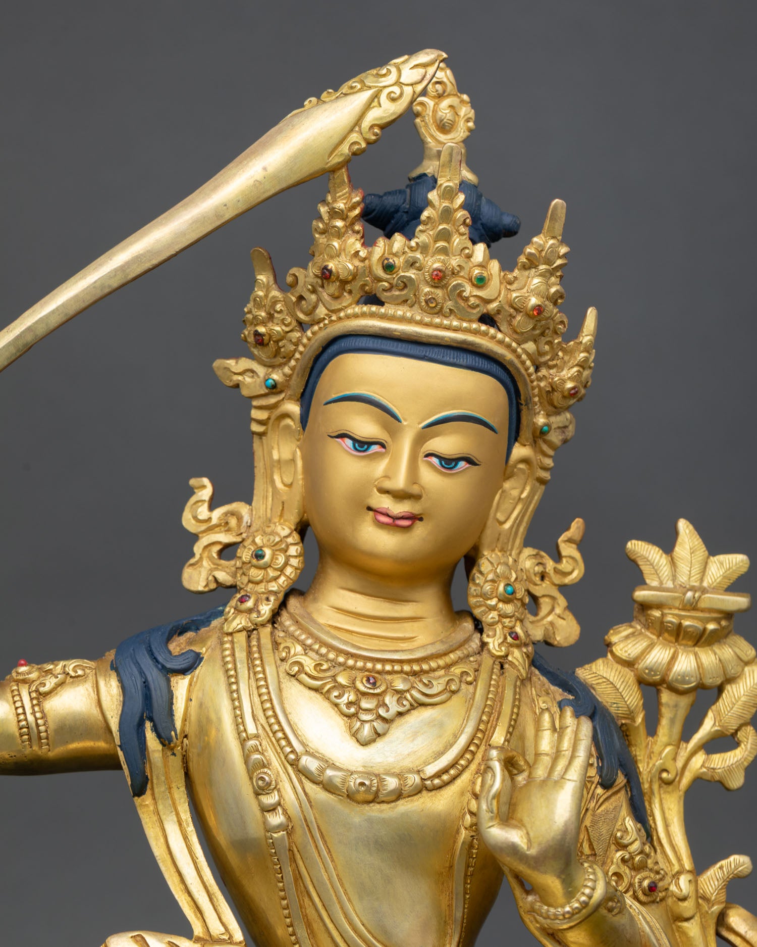 Close up Manjushri face with gold painted expression serene wisdom five jewel crown and detailed Newari artisan craftsmanship