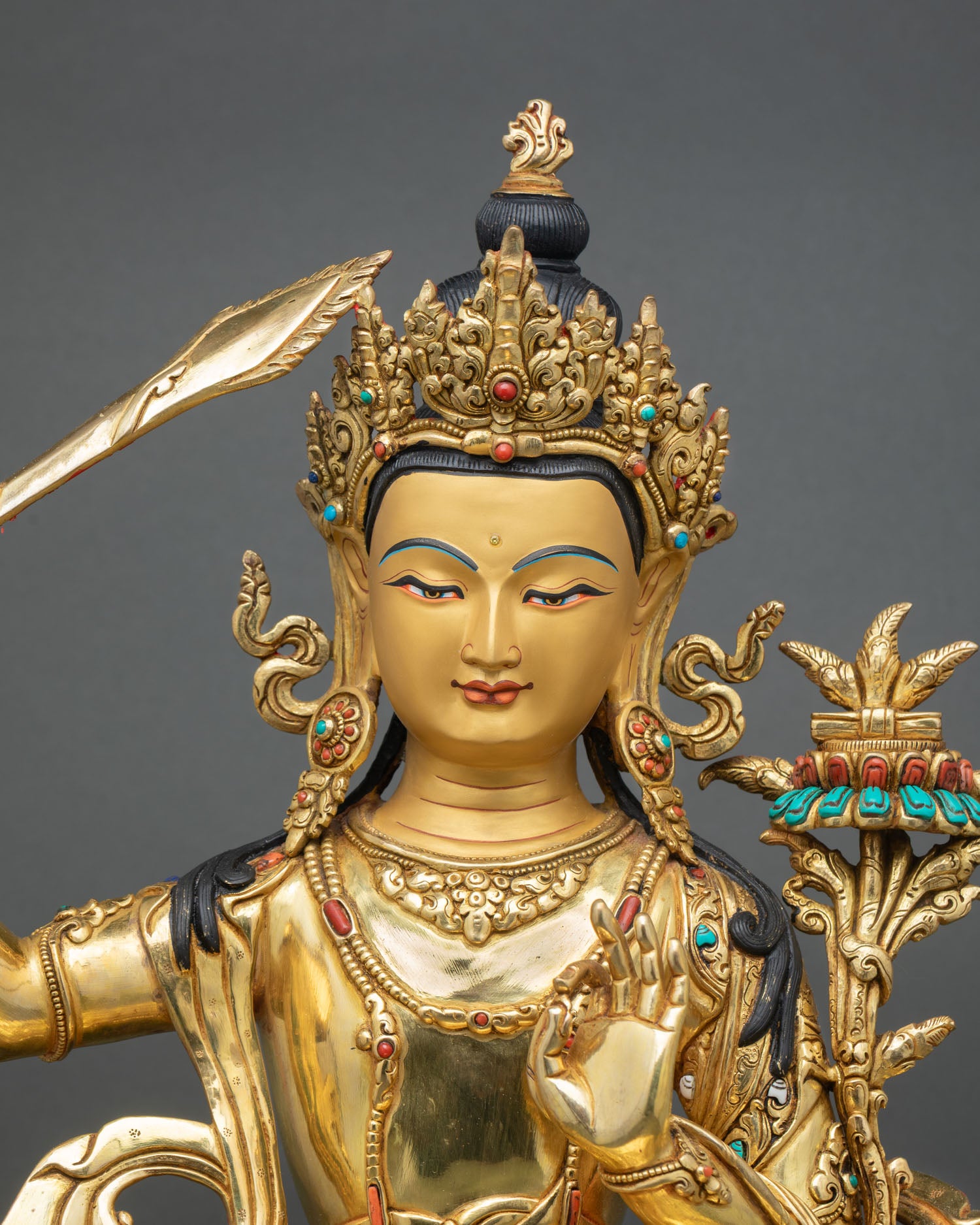 Close up Manjushri wisdom deity face with jeweled crown and gold painted details