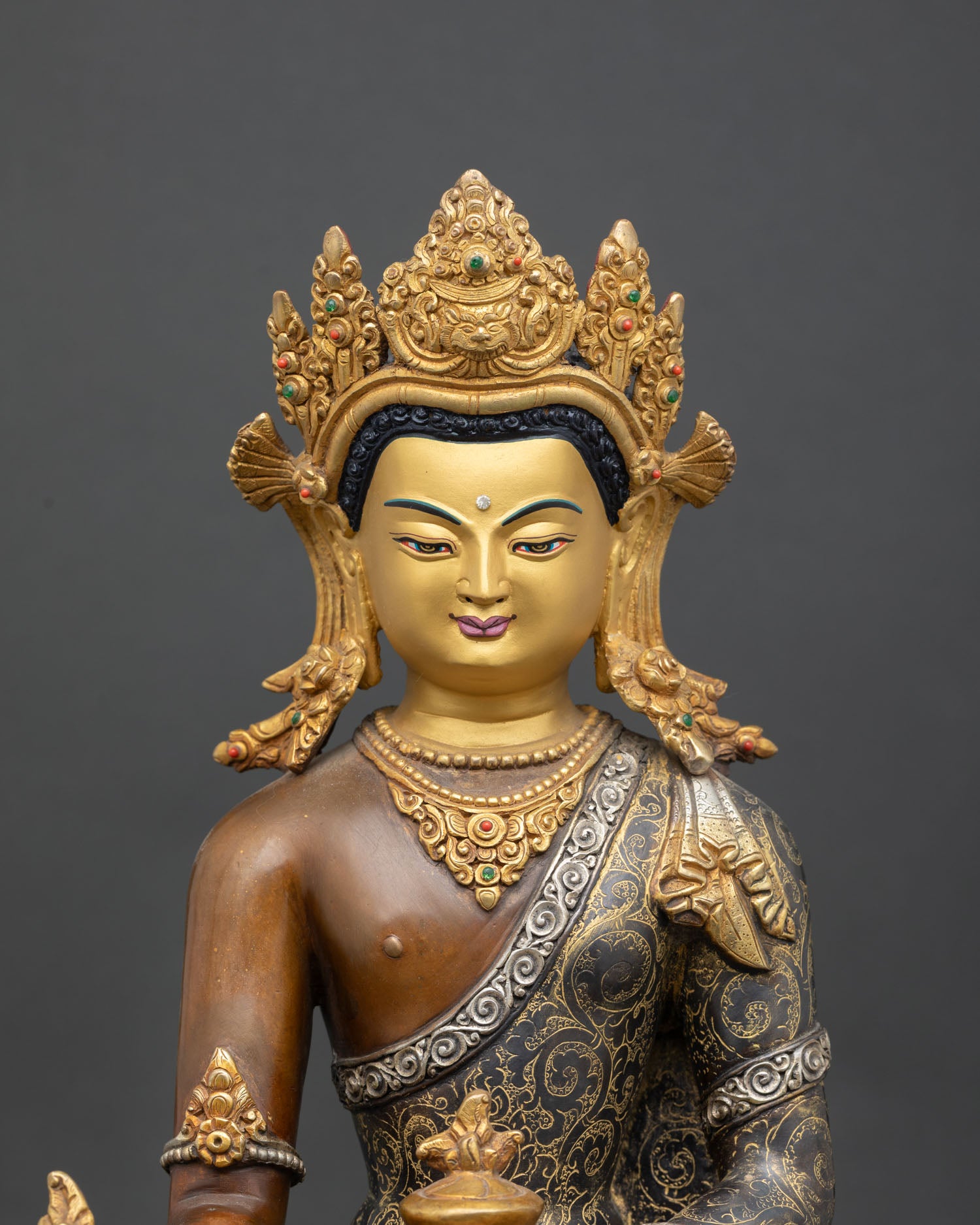 Close up Medicine Buddha face detail gold painted serene expression Himalayan Buddhist craftsmanship jeweled crown intricate lost wax casting deity statue
