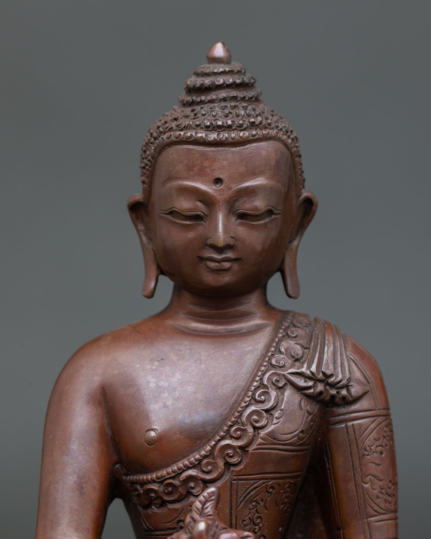 Close up Medicine Buddha statue detail floral robe carvings serene face Newari artisan craftsmanship copper sculpture