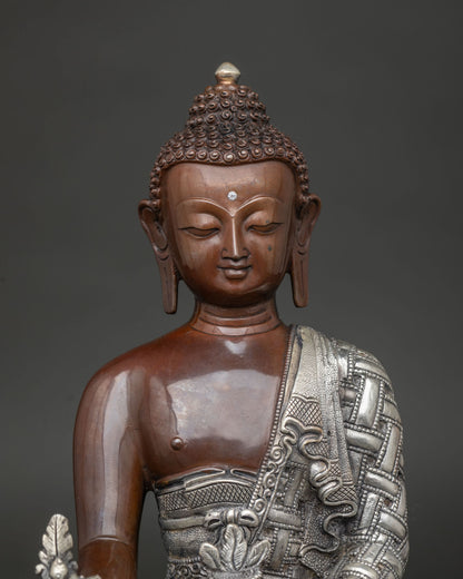 Close up medicine buddha statue showing silver plated robe details and intricate newari carving.