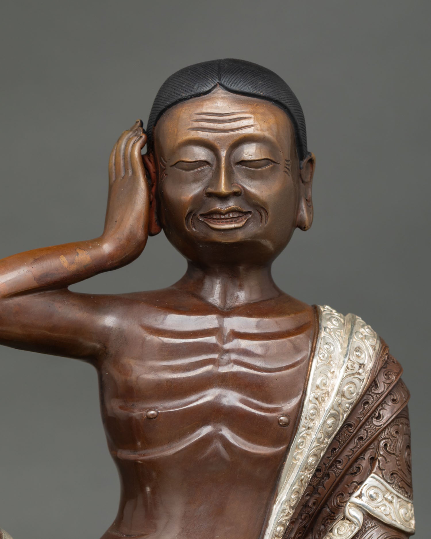 Close up Milarepa Buddhist master statue with listening mudra, detailed facial expression and traditional Himalayan craftsmanship