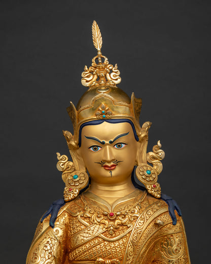 Close up of 24K gold-gilded Padmasambhava sculpture showing intricate incised robes and vajra.