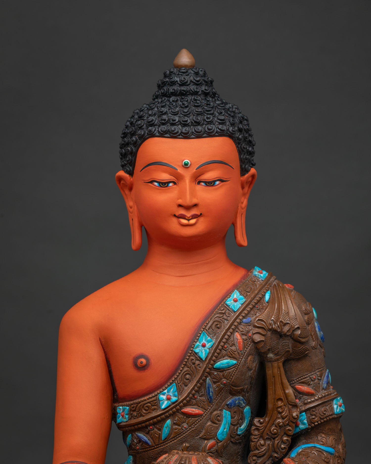 Close-up of acrylic-painted Shakyamuni Buddha statue showing hand-carved robe and stone inlay detail