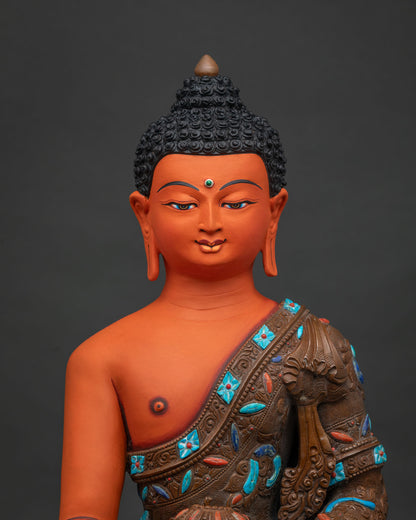 Close-up of acrylic-painted Shakyamuni Buddha statue showing hand-carved robe and stone inlay detail