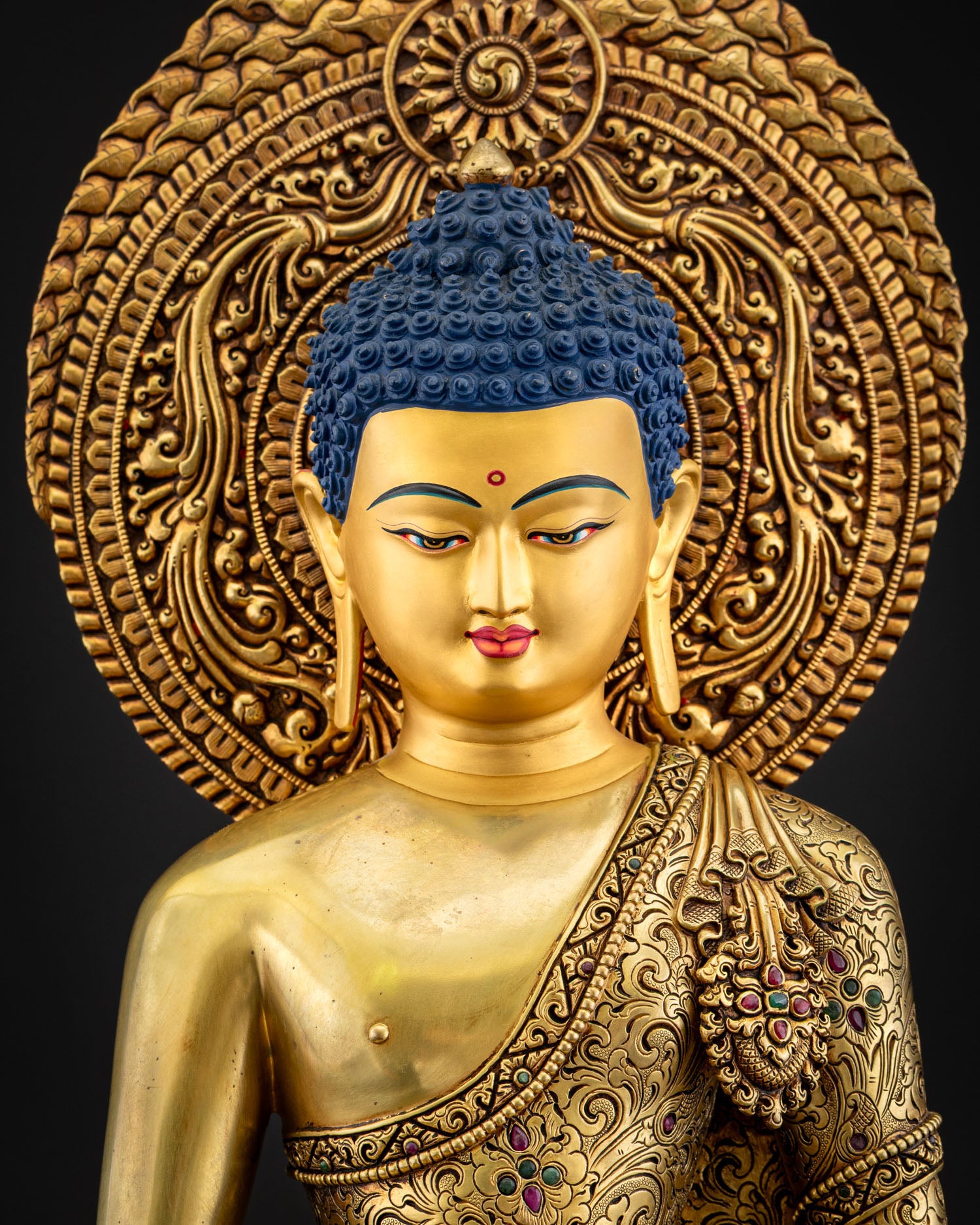 Close‑up of Amitabha Buddha statue showing gold fire‑gilded robe with floral motifs and gemstone inlays