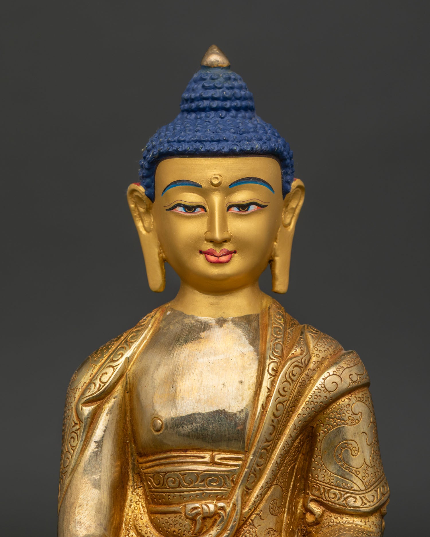Close up of Amitabha Buddha Statue with gold painted face and hand carved monk robe.