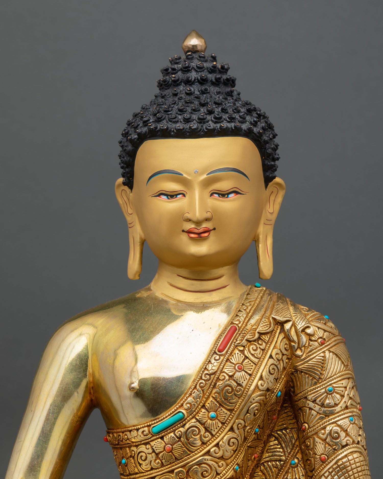 Close up of Amitabha Buddha statue with turquoise and coral stone inlay and floral robe