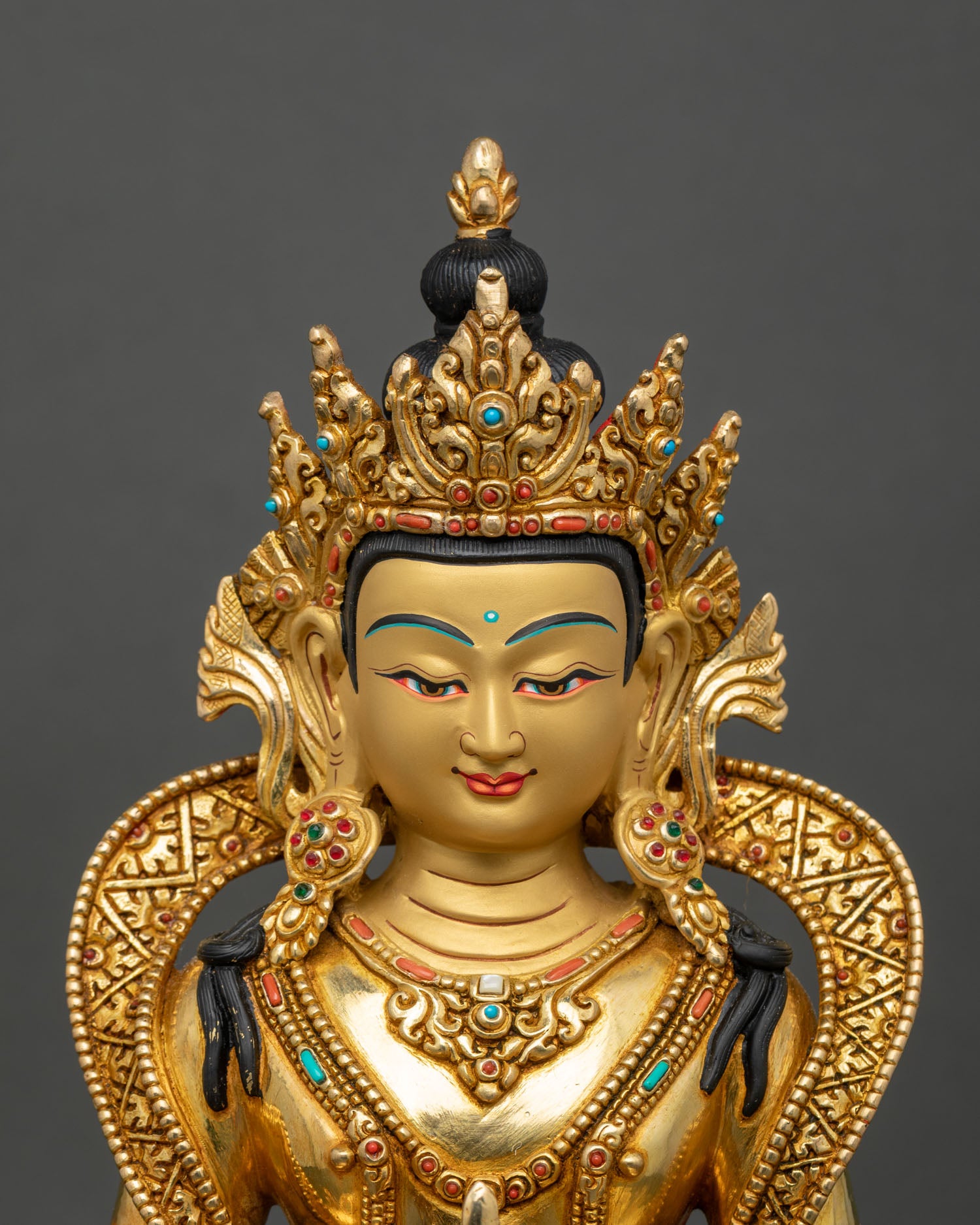 Close up of Amitayus gold-painted face holding medicinal vase for longevity and healing