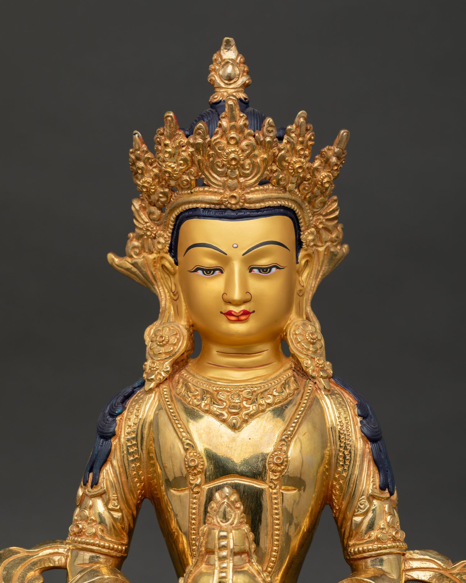Close up of Amitayus statue face with gold paint and fine Buddhist craftsmanship