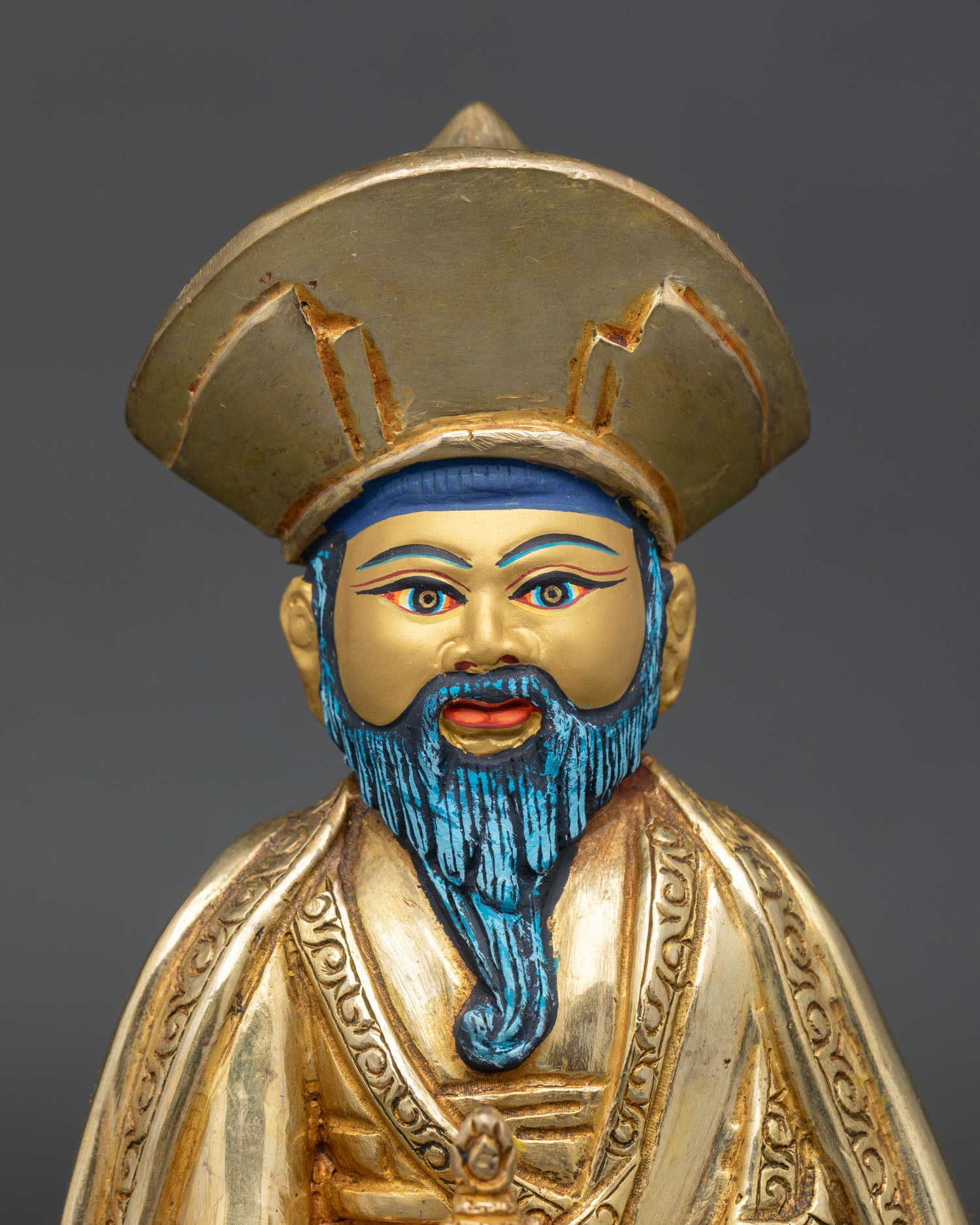 Close up of bearded lama face showing gold painted features traditional hat and detailed Nepalese craftsmanship