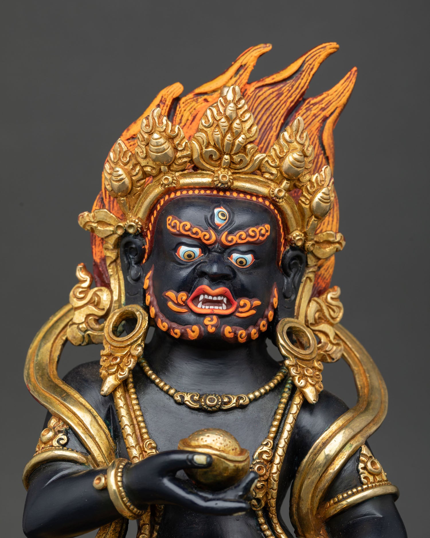 Close up of Black Dzambhala Buddhist statue with sacred gold gilded accents