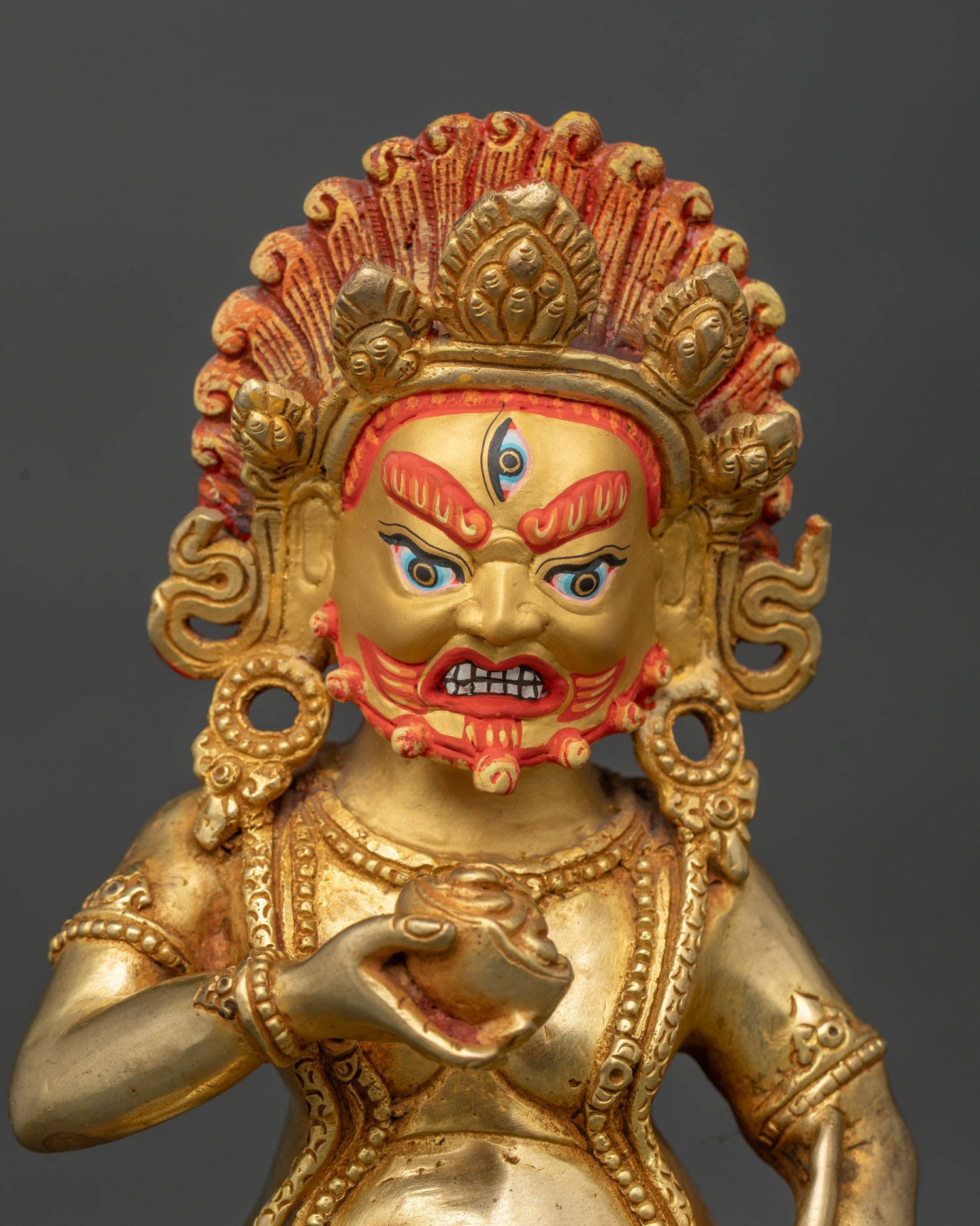 Close up of Black Dzambhala wealth protector statue showing fierce expression and sacred ornaments