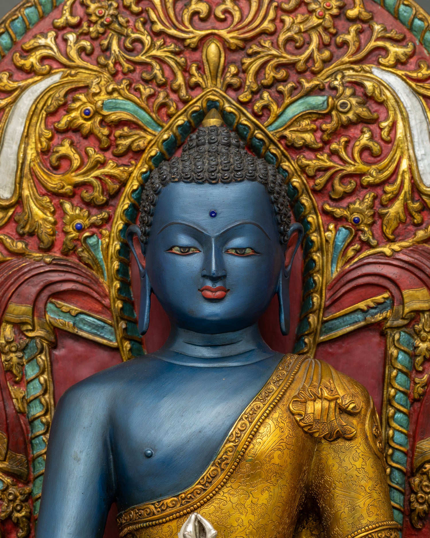 Close up of blue Akshobhya Buddha statue wearing gold robe with silver vajra from Nepal