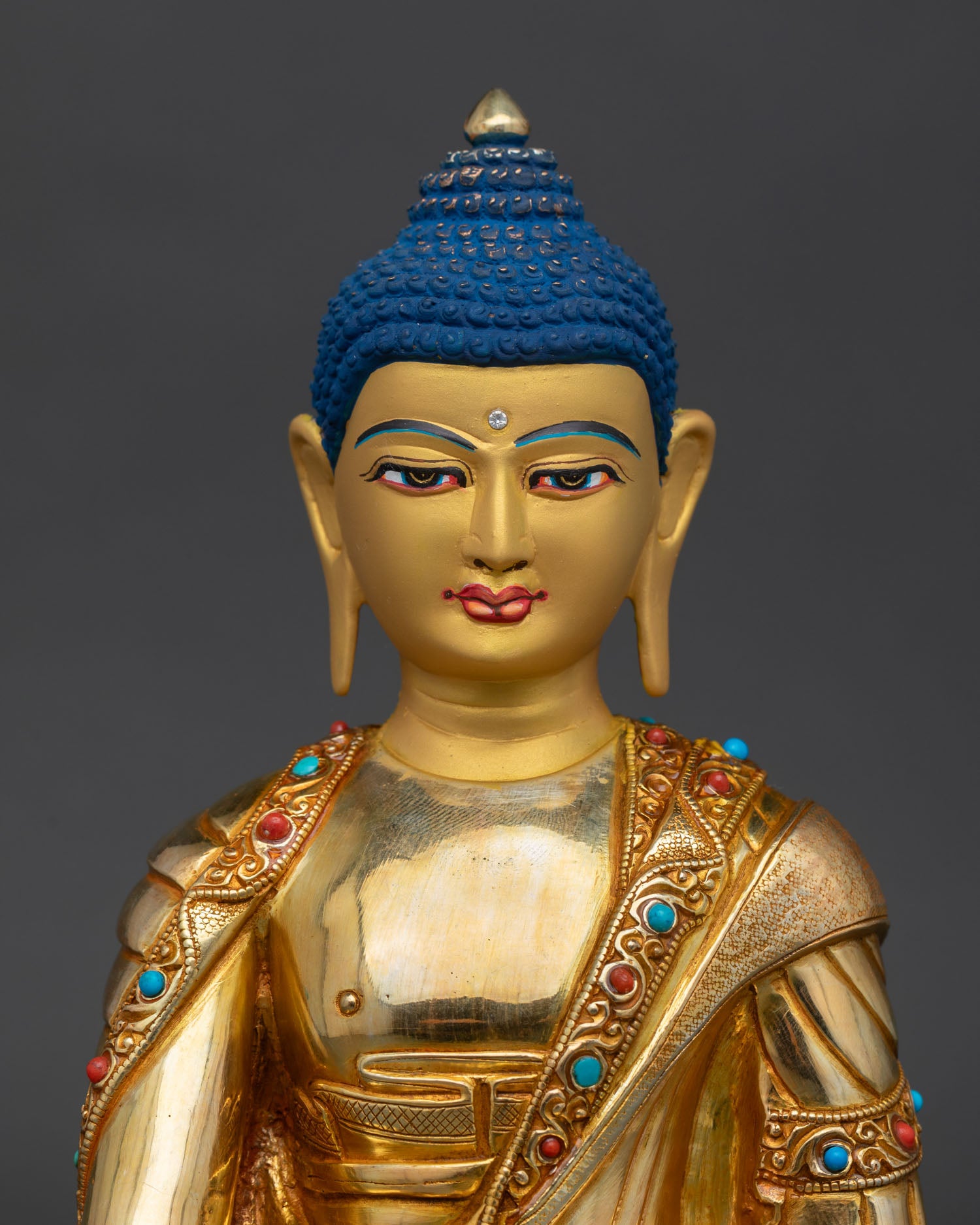 Close up of Buddha Shakyamuni featuring a serene gold-painted face 