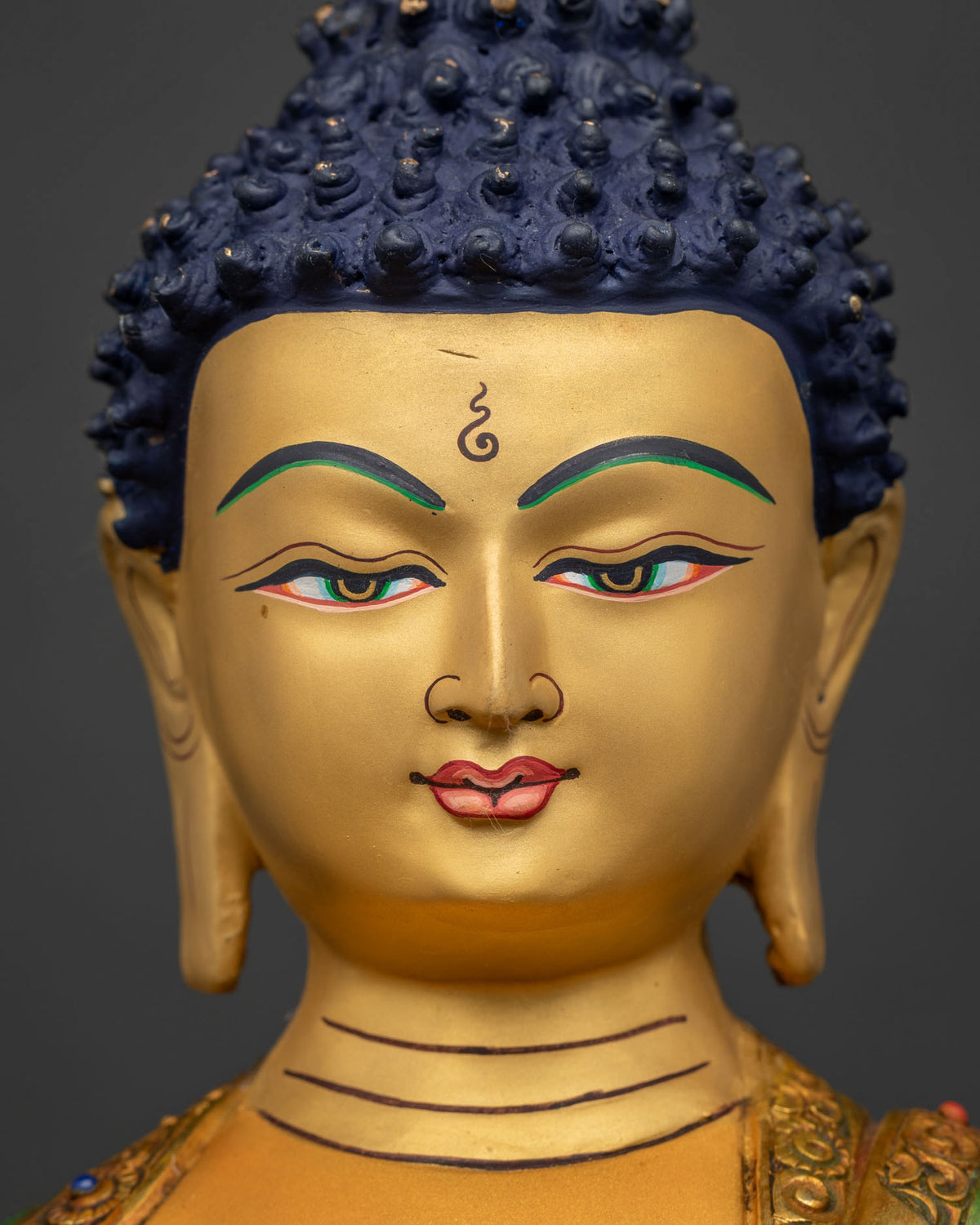 Close-up of Buddha's face with gold pigment and softly lowered eyes