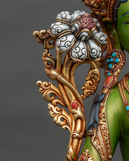 Close-up of carved white lotus flower on gilded stem of Green Tara statue with gemstone center