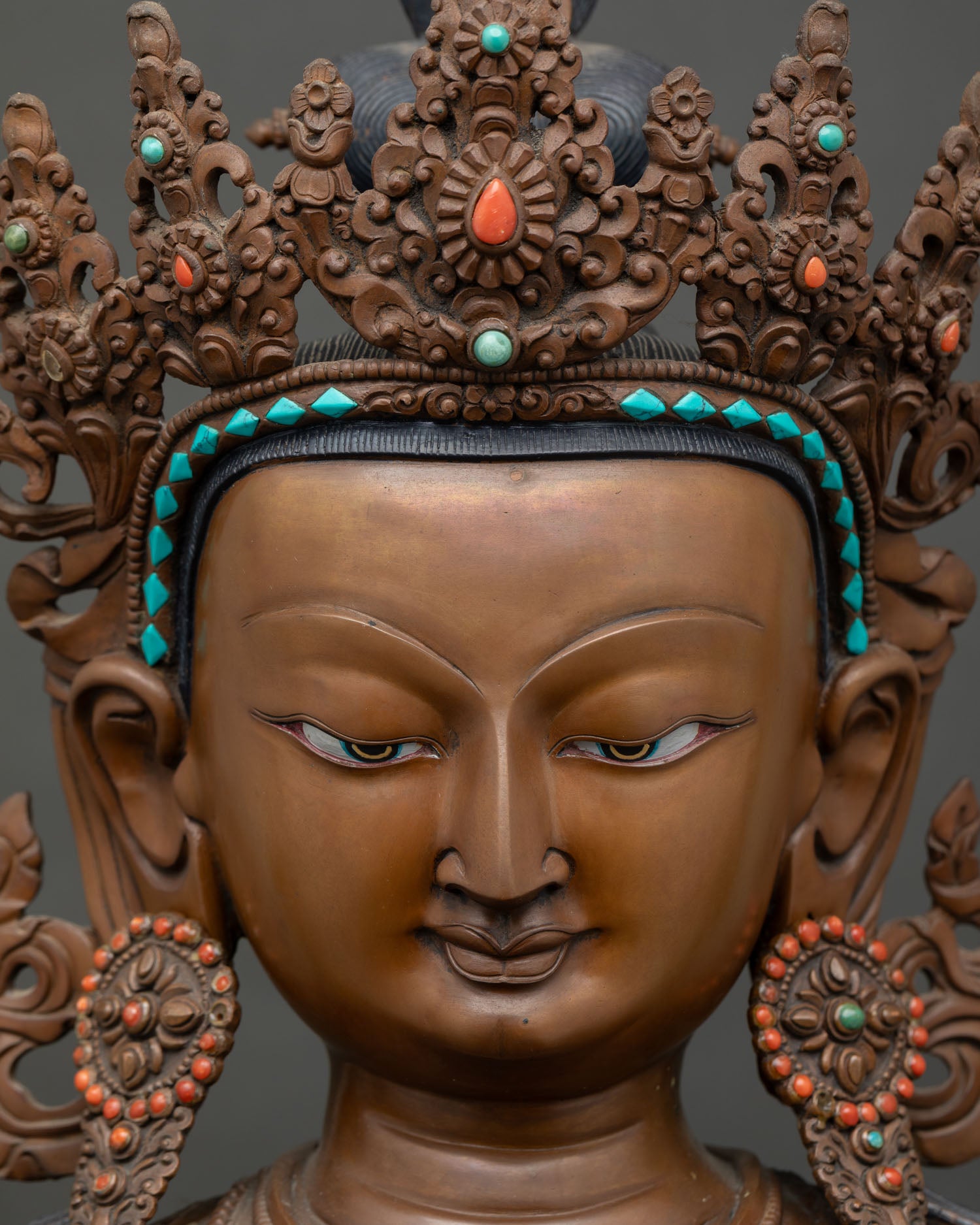 Close-up of Chenrezig's hand-painted face with serene expression and turquoise crown