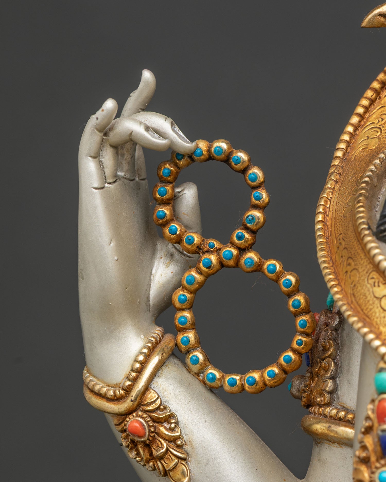 Close-up of Chenrezig statue's hand holding crystal rosary, symbol of purity and mindfulness