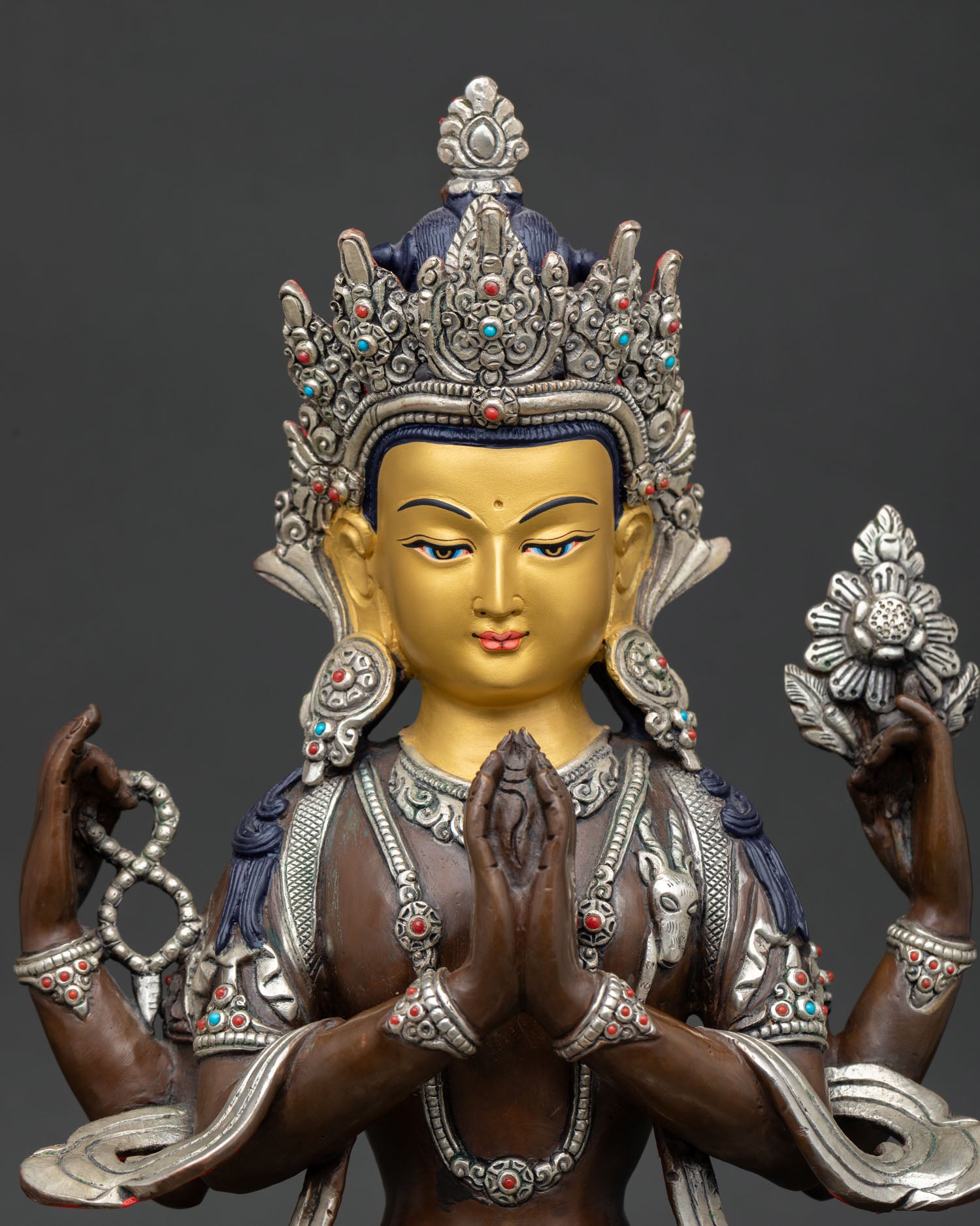 Close-up of Chenrezig statue with gold-painted face, turquoise coral crown and sacred ornaments.