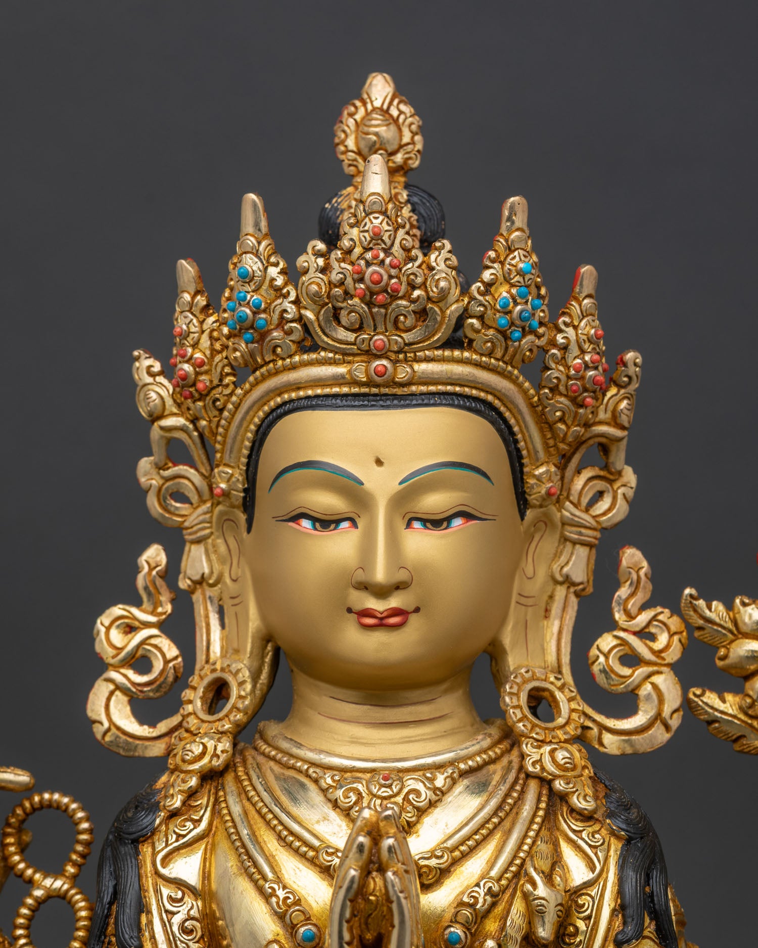 Close up of Chenrezig’s serene hand-painted face with semi-precious stones
