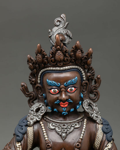 Close up of Dzambhala face with fierce compassionate expression in oxidized copper sculpture