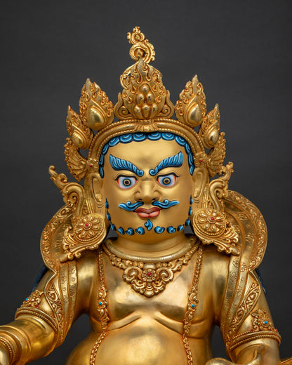 Close up of Dzambhala statue gold painted face citron fruit and jewel spewing mongoose details