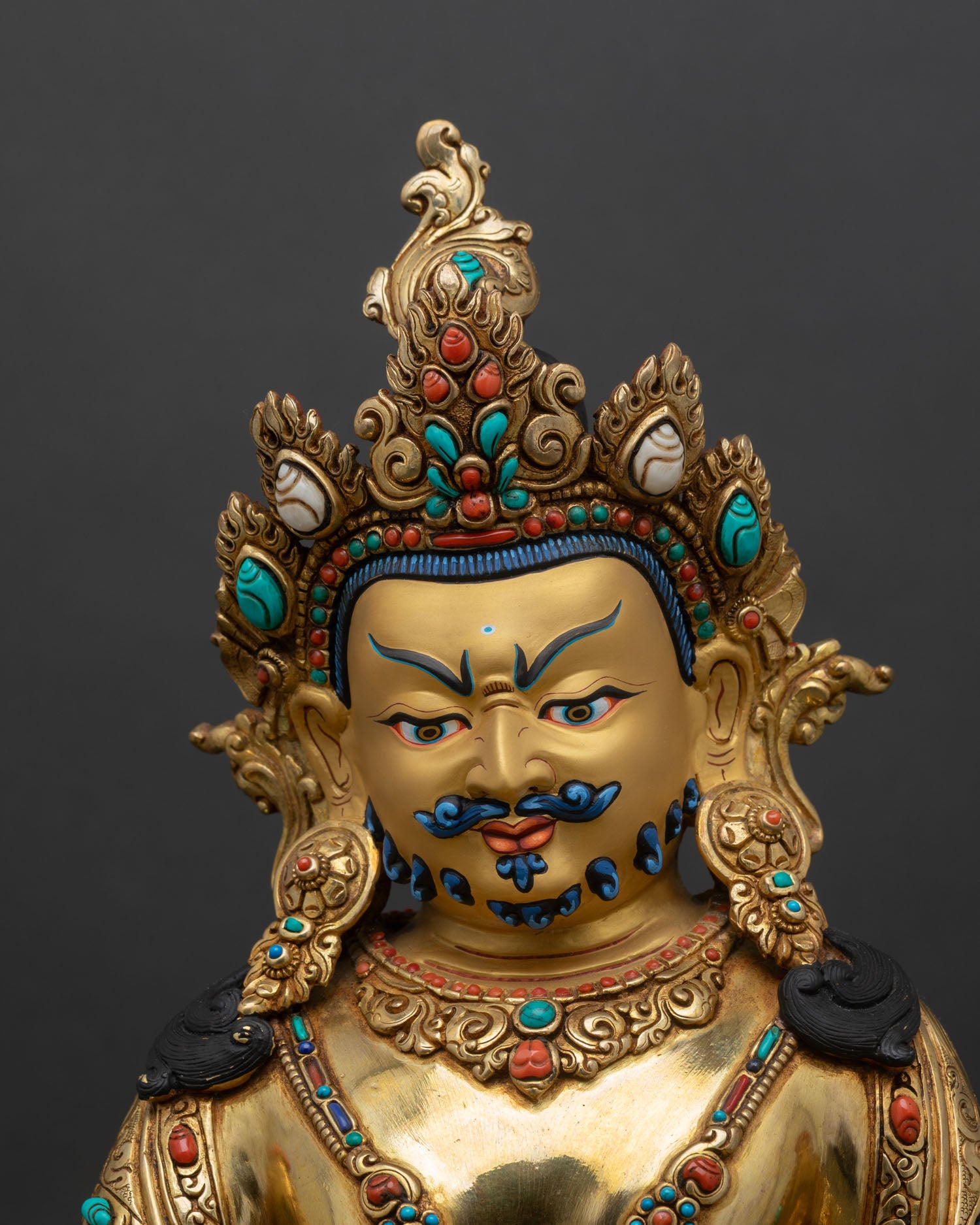close up of dzambhala statue showing gold gilding and intricate copper details