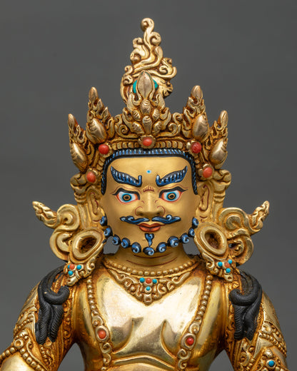 Close-up of Dzambhala statue showing gold gilding and intricate lotus throne details