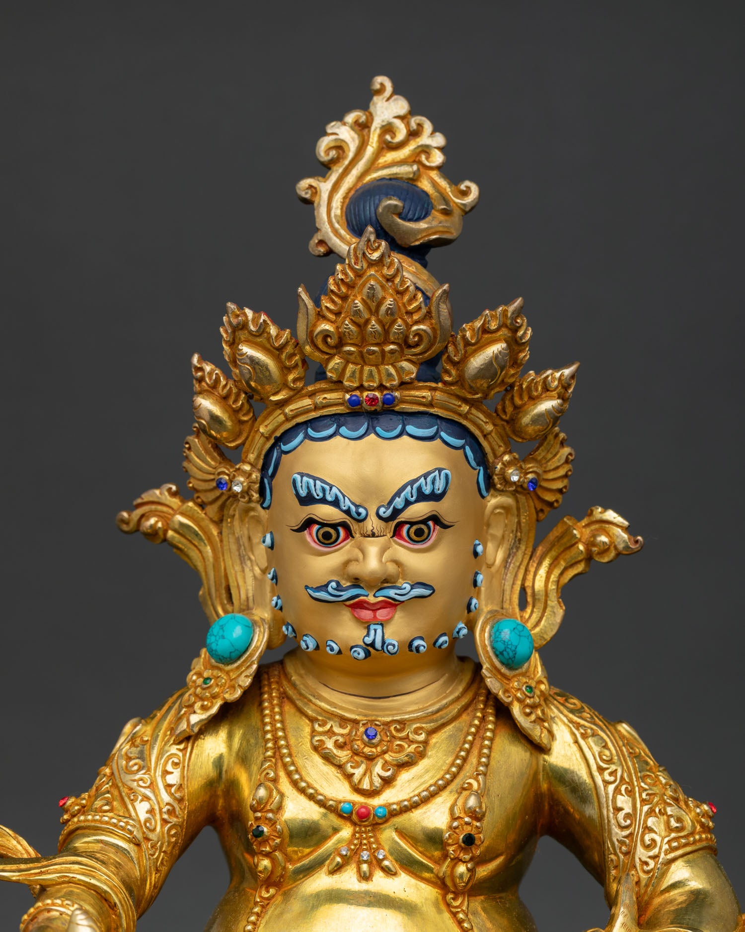 Close-up of Dzambhala Statue showing gold-painted face, intricate crown, and semi-precious stone details by Newari artisans