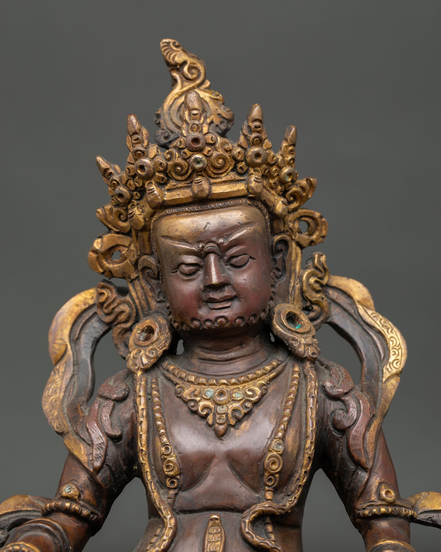 close-up of dzambhala wealth deity face showing intricate handmade copper craftsmanship