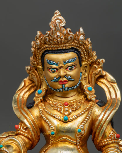 Close-up of Dzambhala wealth deity statue showing gold painted face and fine details