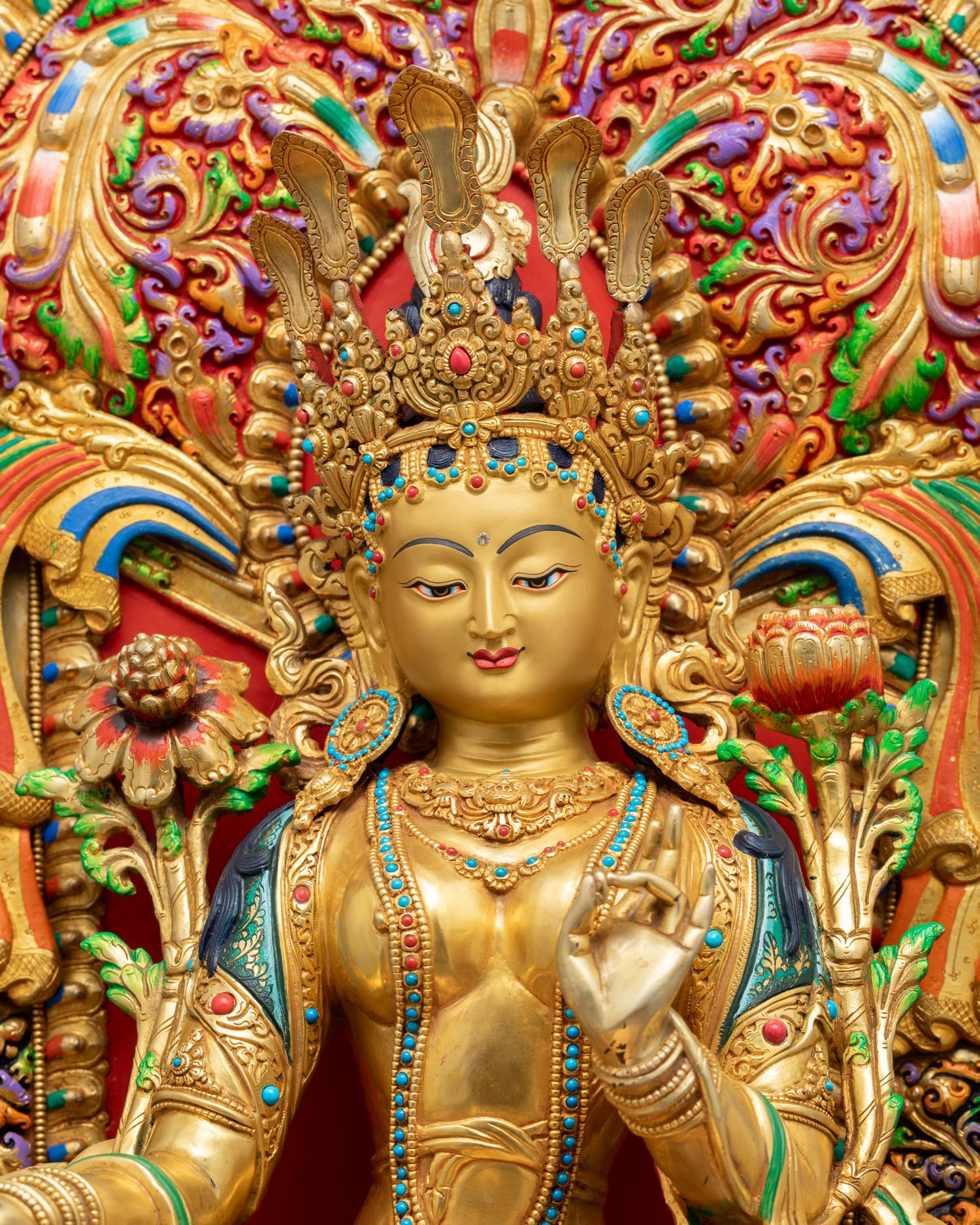 Close-up of enthroned Green Tara statue with ornate prabhavali, coral turquoise gemstone inlays